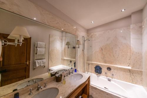 a bathroom with a tub and a sink and a tub at Auberge Saint Walfrid Hôtel Restaurant & Spa in Sarreguemines