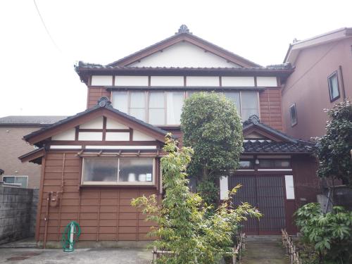 a brown and white house with a gate at Tsunagian TABI-NE in Kanazawa