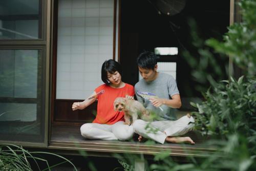 twee mensen op een veranda met een hond bij Tsunagian TABI-NE in Kanazawa