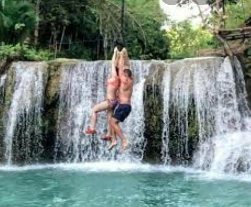 two people jumping off a waterfall into the water at First Baby Bytes Guest House in Siquijor