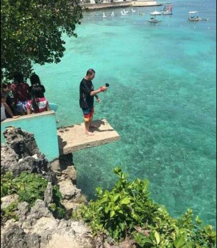a man standing on a dock taking a picture of the water at First Baby Bytes Guest House in Siquijor