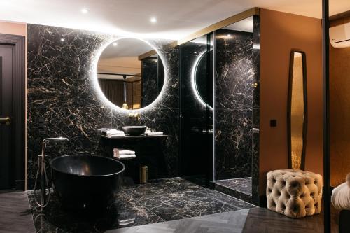 a black bathroom with a tub and a mirror at Hotel Britannique in Maastricht
