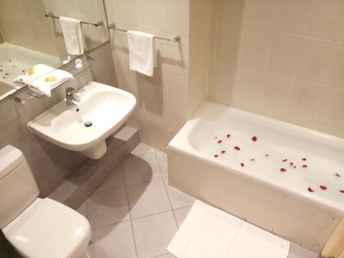 a bathroom with a sink and a tub and a toilet at Oriental Palace Hotel in Manama