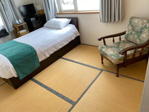 a hotel room with a bed and a chair at Sirogane Free Harbour Hotel in Biei