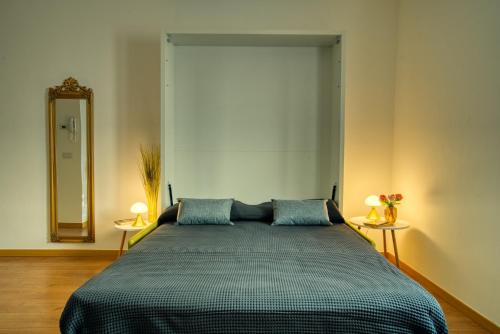 a bedroom with a bed with two lamps and a mirror at CaseOspitali - Casa Diva, monolocale in centro storico in Cernusco sul Naviglio