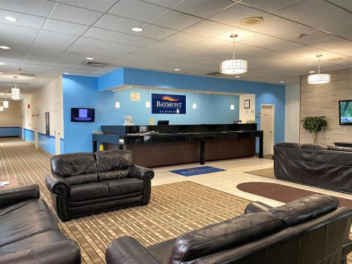 a waiting room with leather chairs and a piano at Baymont by Wyndham Queensbury/Lake George in Queensbury