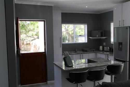 una cocina con encimera y algunos taburetes en ella en Milo's Sky Grey Guest House - No Load shedding en Ciudad del Cabo