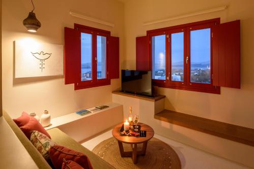 a living room with red windows and a table at Potnia Theron Suites in Akrotiri