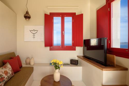 a living room with red windows and a tv at Potnia Theron Suites in Akrotiri