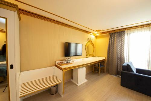 a room with a desk with a television and a couch at Empire Suite Hotel in Istanbul