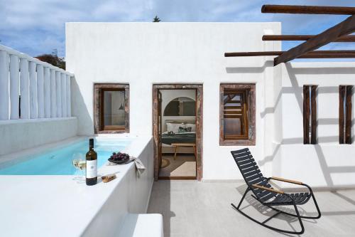 a white house with a pool and a chair at Winery Hotel 1870 in Fira
