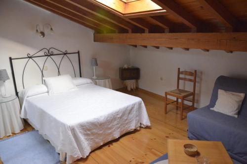 a bedroom with a white bed and a chair at Casa de la Parra in Mogarraz