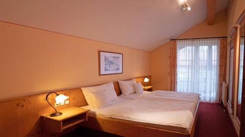 a bedroom with a bed with white sheets and pillows at Ferienwohnungen am Kurpark in Roßhaupten