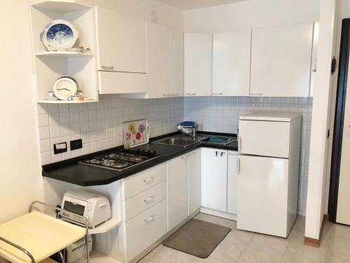 a small kitchen with white cabinets and a sink at Villa Marta in Grado