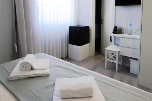 a bedroom with a bed with towels on it at Golden Beach Guest House & Rooftop Bar in Faro