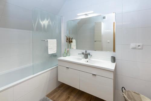a white bathroom with a sink and a mirror at Apartmány Lesy a Lúky - V srdci Tatier in Vysoke Tatry - Horny Smokovec