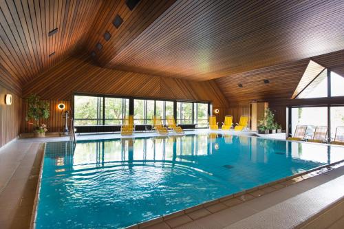 une grande piscine avec des chaises jaunes dans un bâtiment dans l'établissement Haus Große Kettler, à Bad Laer