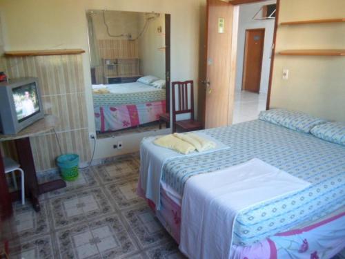 a bedroom with two beds and a tv and a mirror at Hostel Palmas Centro Da Cidade in Palmas