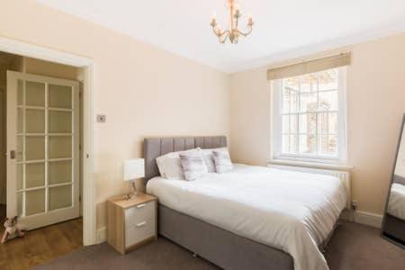 - une chambre avec un grand lit et une fenêtre dans l'établissement Regency apartment - private entrance & courtyard, à Cheltenham