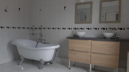La salle de bains est pourvue d'une baignoire, d'un lavabo et de miroirs. dans l'établissement Les Hauts de Proisy, à Proizy