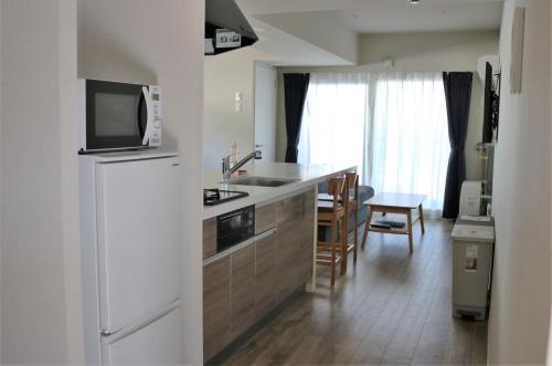 a kitchen with a white refrigerator freezer next to a table at Stay's OTARU in Otaru