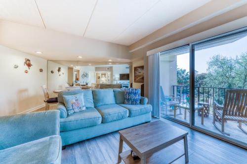 a living room with a blue couch and a balcony at Forest Beach Villas in Hilton Head Island