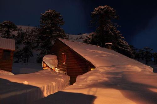 a log cabin covered in snow at night at Lodge Tikilen Caviahue in Caviahue