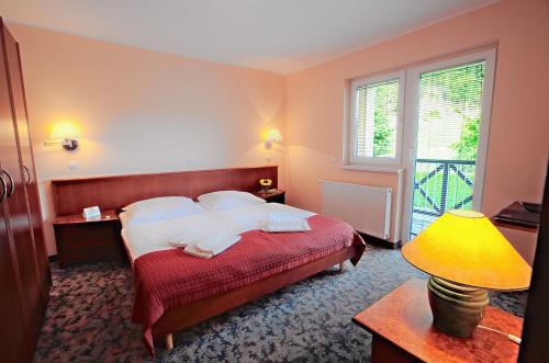 a bedroom with a bed and a lamp and a window at Terme Olimia - Aparthotel Rosa in Podčetrtek