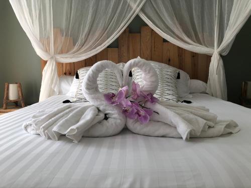 Una cama con toallas y flores encima. en Gîte Maracudja vue sur mer, en Capesterre-Belle-Eau