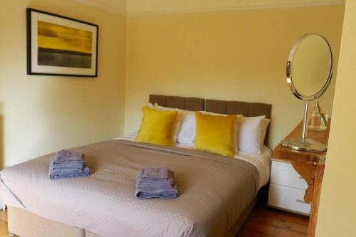 um quarto com uma cama com almofadas amarelas e um espelho em Self contained stylish city home em Norwich