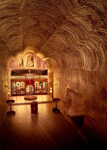 a room with a stone wall and a room with stools at Ali's Underground Studio in Coober Pedy