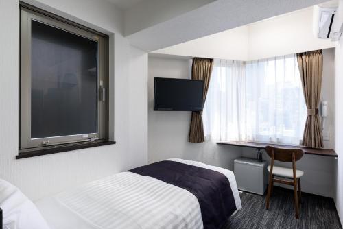 a hotel room with a bed and a flat screen tv at Shinbashi Urban Hotel in Tokyo