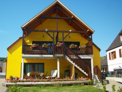 a yellow house with a balcony with flowers on it at Alsace Appartements Meyer-Krumb in Sigolsheim