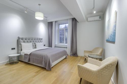 a bedroom with a bed and two chairs and a window at Opera Apartments Almaty in Almaty