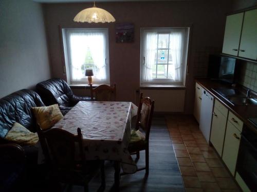 a living room with a table and a couch and a kitchen at Ferienhof zur alten Linde in Holtgast