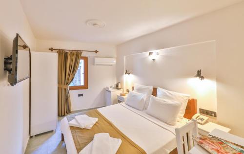 a bedroom with a white bed with white pillows at Zinbad Hotel Kalkan in Kalkan