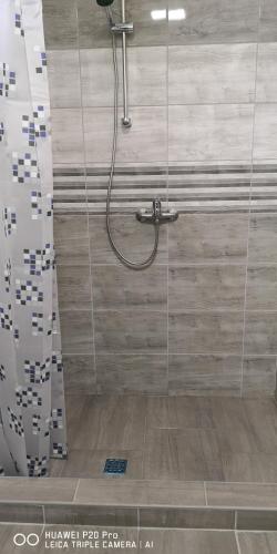 a shower in a bathroom with a shower curtain at Kifog-Lak Vendégház in Poroszló