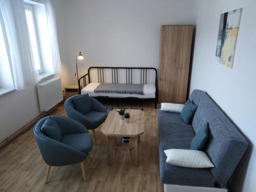 ein Wohnzimmer mit einem Sofa, 2 Stühlen und einem Bett in der Unterkunft Apartmán U Dubu in Jablonné nad Orlicí