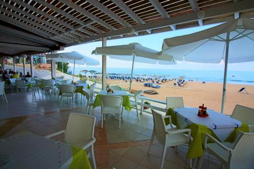 a restaurant with tables and chairs and a beach at Santa Barbara Lakis Apartments in Perivolion