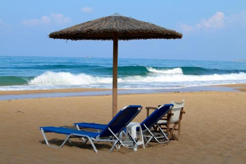 two chairs and an umbrella on the beach at Santa Barbara Lakis Apartments in Perivolion