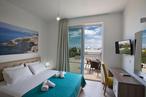 a bedroom with a bed and a desk and a balcony at Polymnia Luxury Villas in Protaras