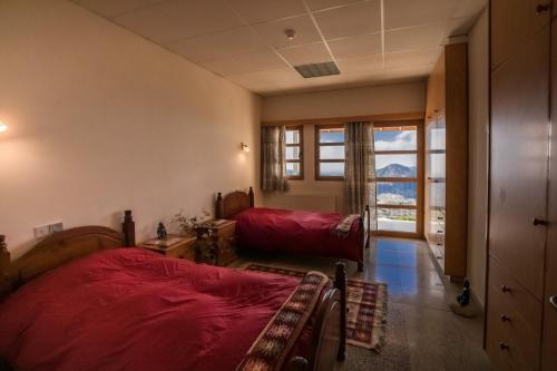- une chambre avec un lit rouge et une grande fenêtre dans l'établissement Retreat Centre Cyprus, à Zoopiyi