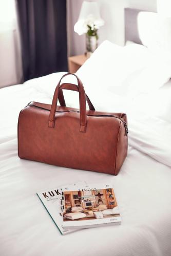 a brown bag sitting on top of a bed with a magazine at Silesia Apartments in Katowice