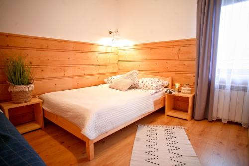 Un dormitorio con una cama con paredes de madera y una ventana en Willa Przy Skoczni, en Zakopane