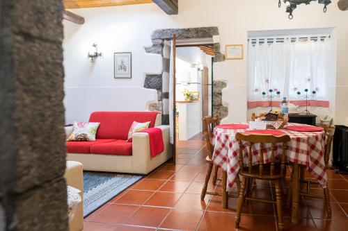 a living room with a table and a red couch at Casa da Agua Quente - AL in Furnas