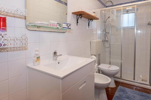 a white bathroom with a sink and a toilet at Casa da Agua Quente - AL in Furnas