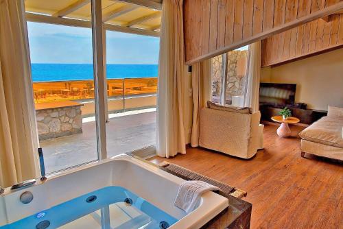 a bath tub in a room with a view of the ocean at Litohoro Olympus Resort Villas & Spa in Plaka Litochorou