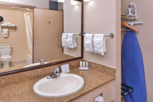 a bathroom with a sink, mirror, and towel rack at Hotel Nova SFO By FairBridge in South San Francisco