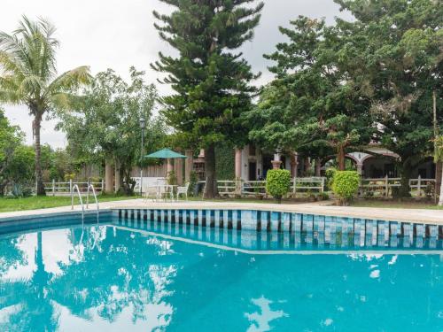 a swimming pool in front of a house with trees at Rancho Hotel El Carmen in Tlapacoyan