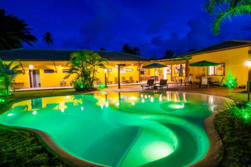 a swimming pool in front of a house at night at Pousada Tropicarim in Itacimirim